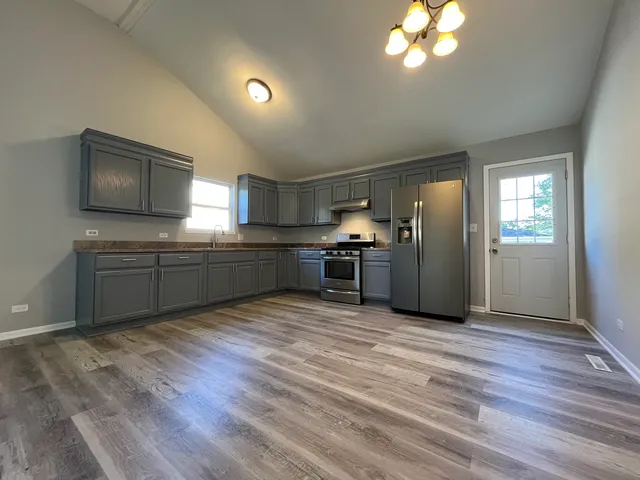 a kitchen with stainless steel appliances granite countertop a refrigerator and a stove top oven