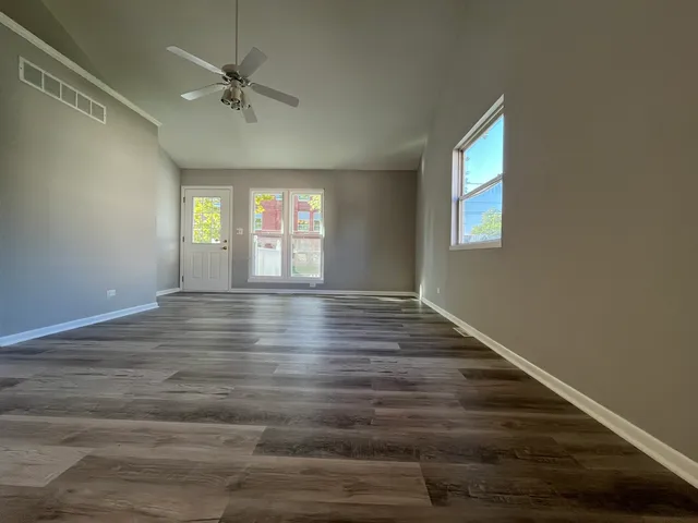 a view of an empty room with window and wooden floor