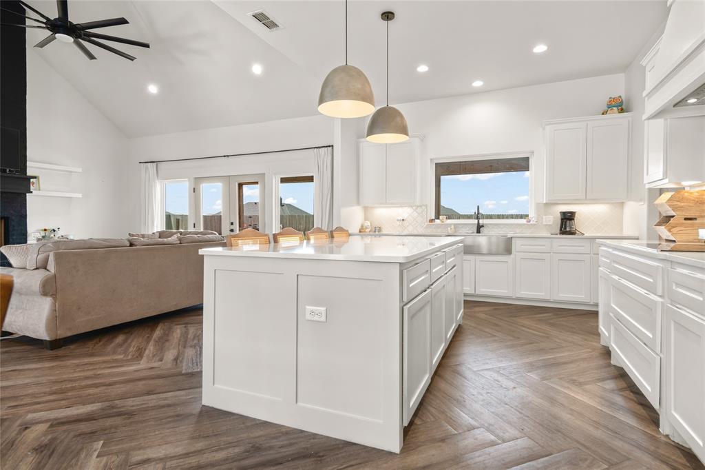 120 Long Ranger Road Abilene, TX 79602 - Photo 9 of 23 Open-concept kitchen and living area featuring wood-finish flooring in a herringbone pattern, a central island with white cabinetry and a light-toned countertop, and recessed lighting throughout