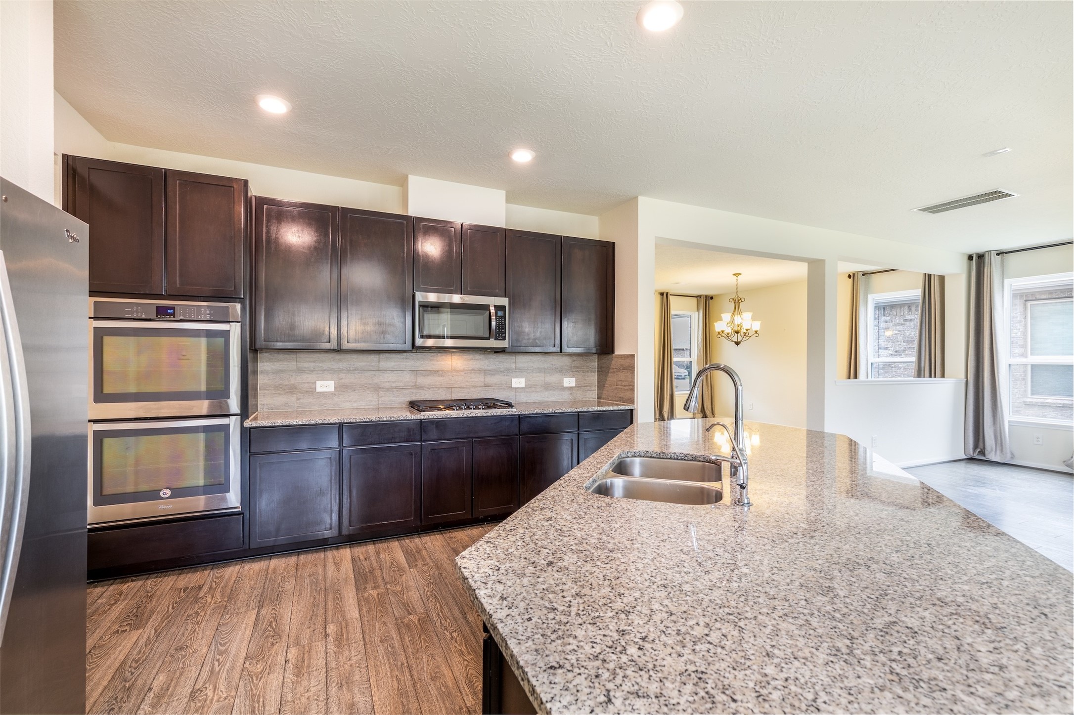 15623 Hanover Breeze Lane Houston, TX 77044 - Photo 9 of 46 a large kitchen with kitchen island granite countertop wooden cabinets a granite counter tops and a stove