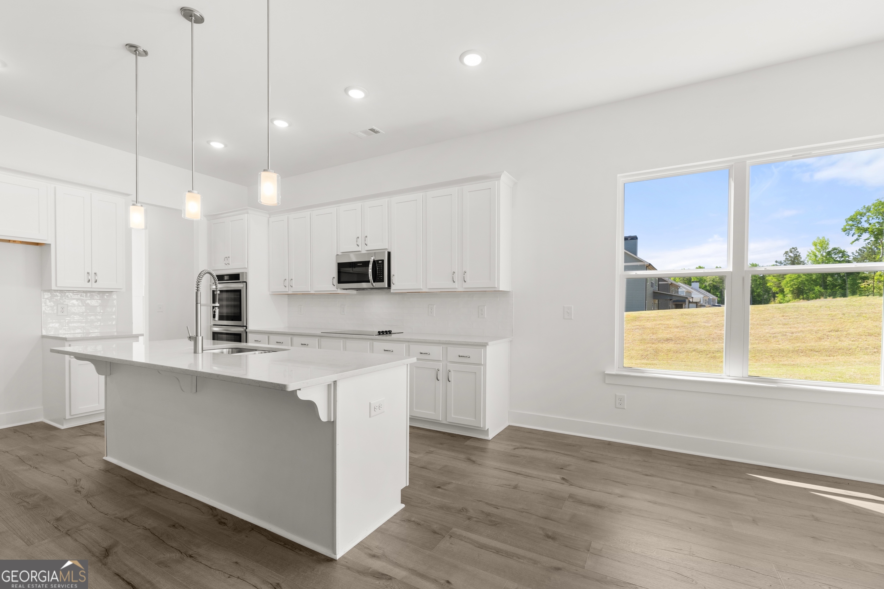 15 Overview Court Hoschton, GA 30548 - Photo 13 of 43 a kitchen with stainless steel appliances granite countertop a sink a stove a refrigerator and island with wooden floor