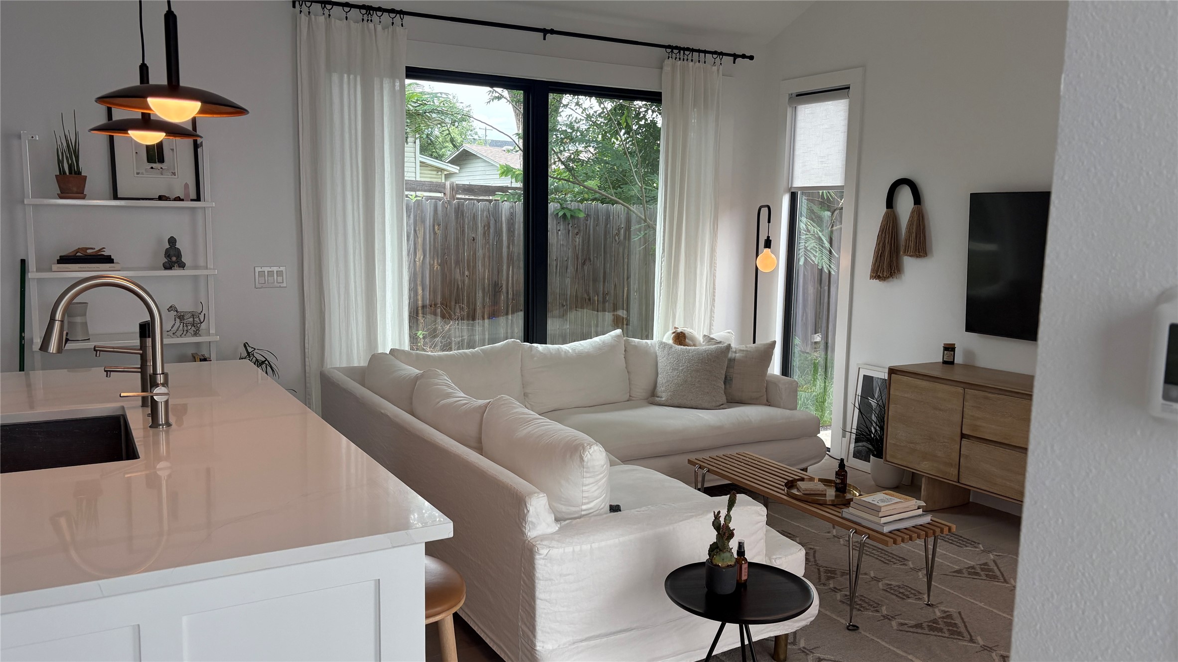 1816 Adina Street, Unit 2 Austin, TX 78721 - Photo 5 of 25 Open-concept living space with large black-framed windows, a built-in kitchen island featuring an undermount sink and pull-down faucet, recessed ceiling lighting, and pendant light fixtures