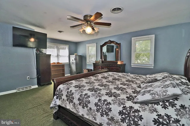 a bedroom with a bed dresser and a large window