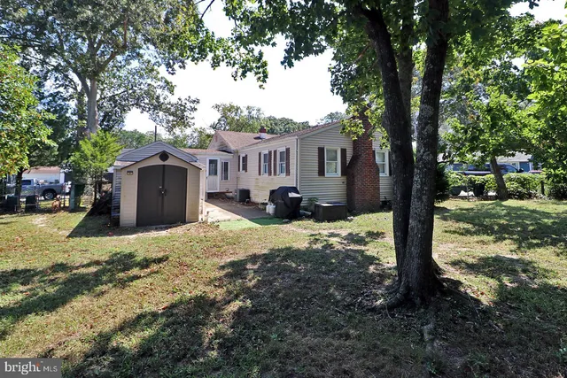 a front view of a house with a yard and large tree