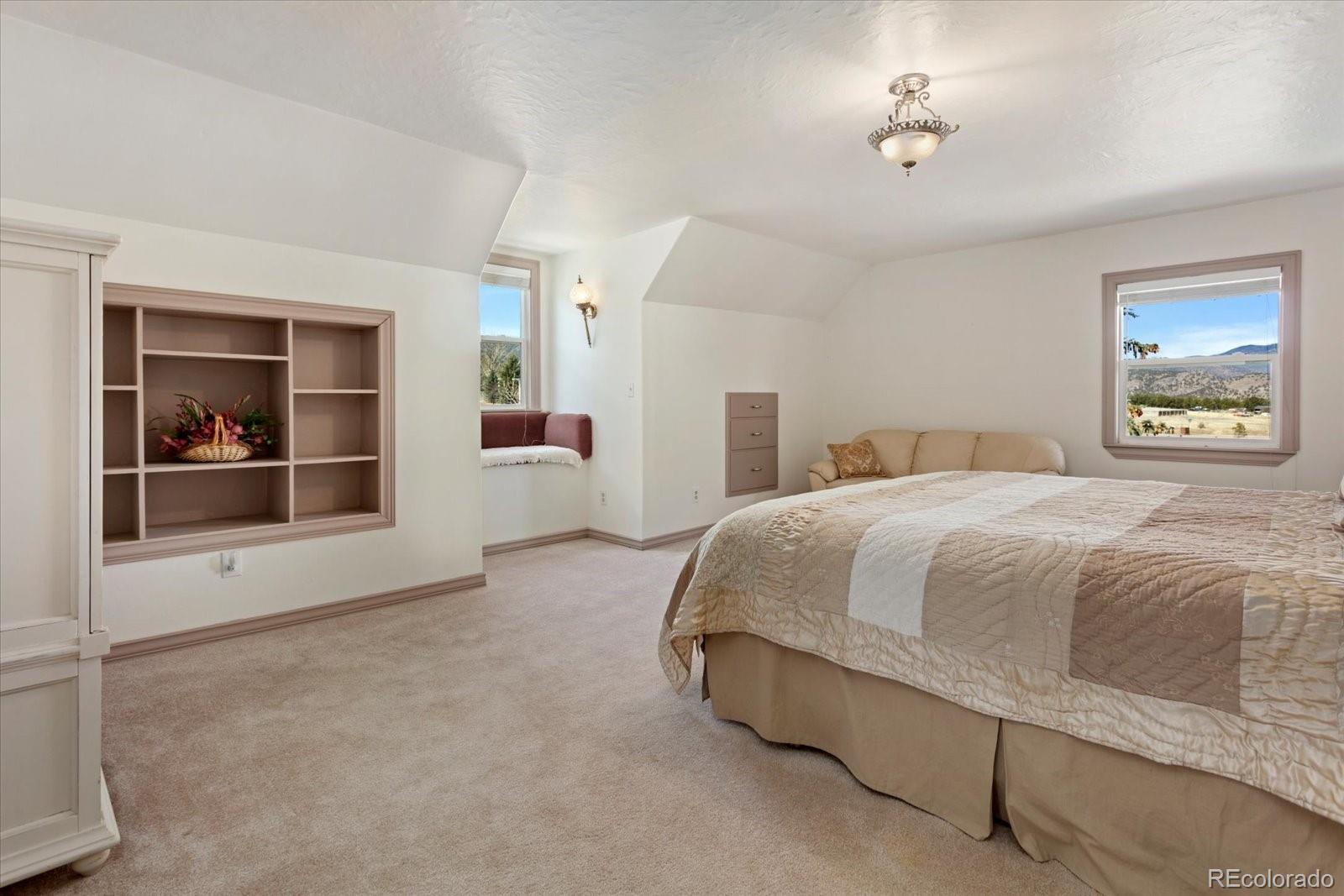 716 West Blarney Stone Road Howard, CO 81233 - Photo 23 of 50 a spacious bedroom with a bed and a chandelier