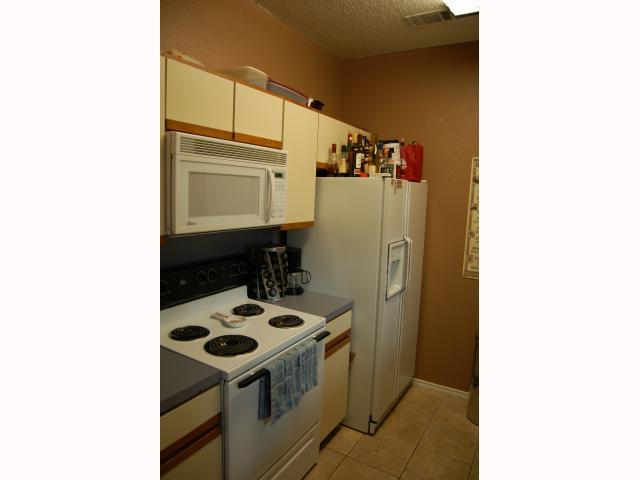 2804 Rio Grande Street, Unit 307 Austin, TX 78705 - Photo 10 of 14 Kitchen featuring white appliances, a textured ceiling, and light tile patterned floors