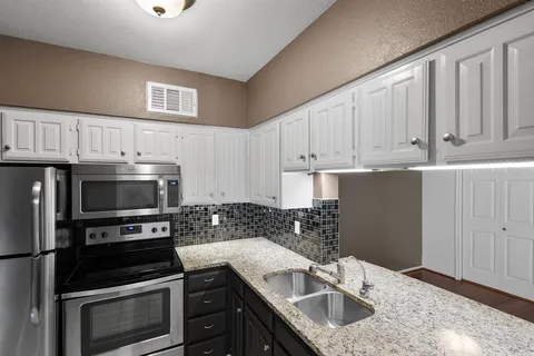 a kitchen with granite countertop a sink cabinets and stainless steel appliances