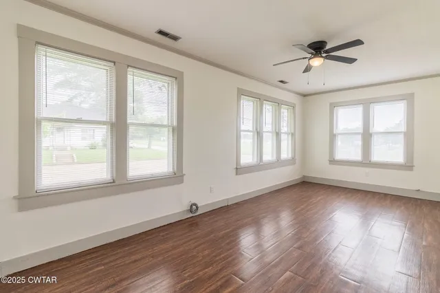 a view of an empty room with wooden floor and a window