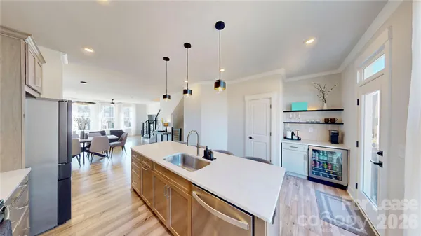 a kitchen with kitchen island a stove a refrigerator a sink a dining table and chairs with wooden floor