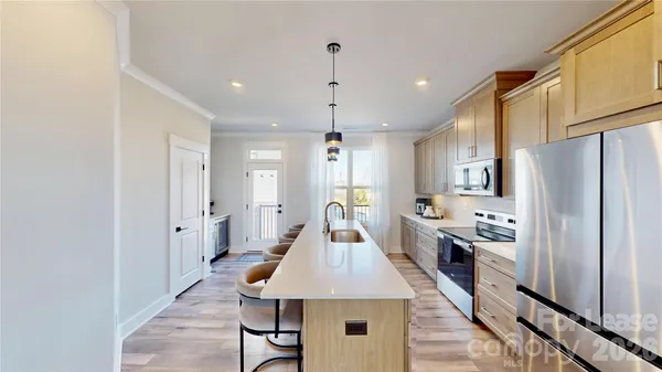 a kitchen with stainless steel appliances kitchen island granite countertop a refrigerator a stove and a sink
