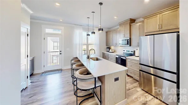 a kitchen with stainless steel appliances a refrigerator a stove a sink dishwasher a dining table and chairs with wooden floor