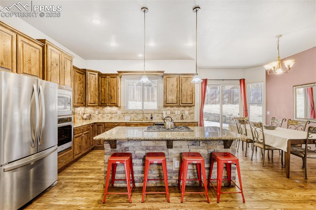 4519 Edwards Place Cascade, CO 80809 - Photo 12 of 47 Kitchen with stainless steel appliances, a kitchen island, tiled backsplash, and a breakfast bar