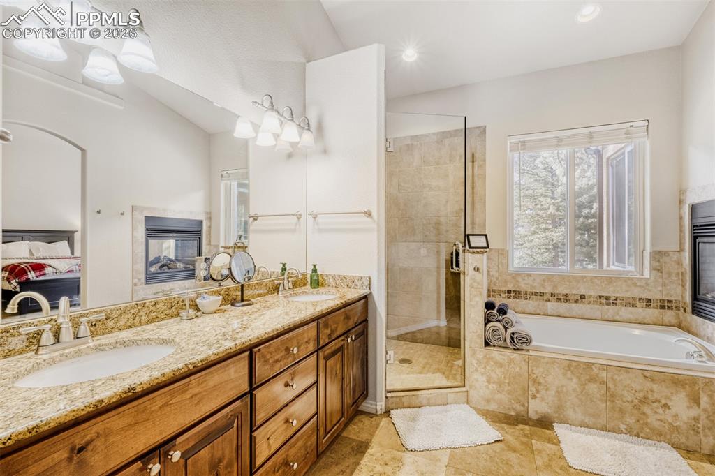 4519 Edwards Place Cascade, CO 80809 - Photo 20 of 47 Ensuite bathroom with double vanity, a garden tub, a stall shower, and recessed lighting and fireplace