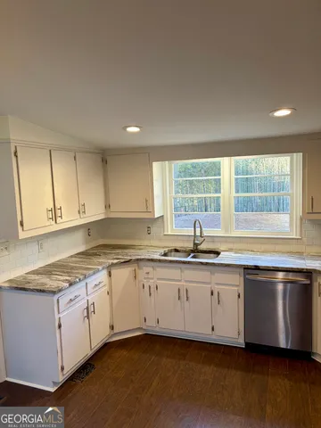 a kitchen with granite countertop a sink and white cabinets