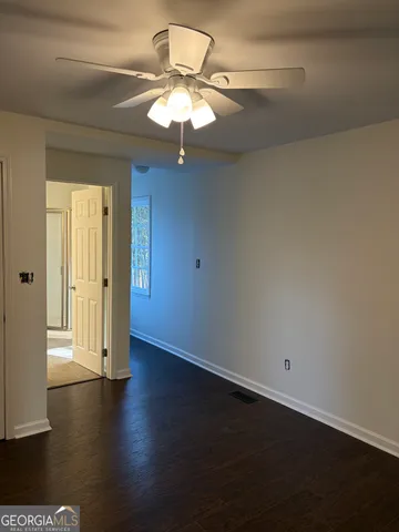 an empty room with wooden floor chandelier fan and windows