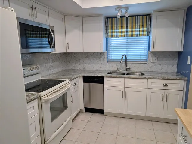 a kitchen with white cabinets appliances and sink