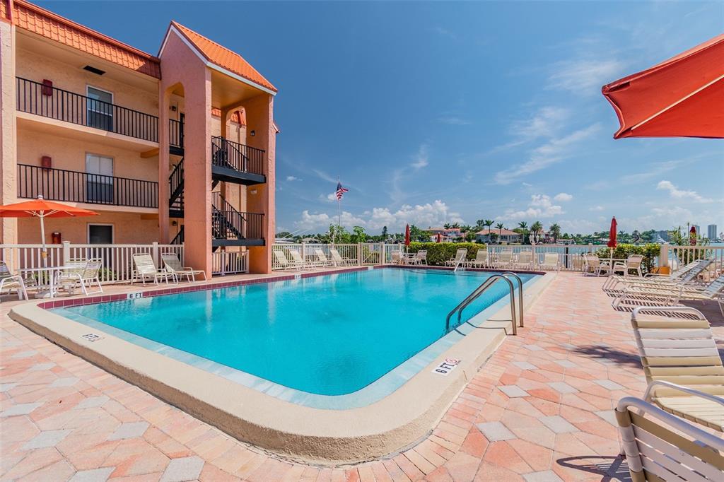 8901 Blind Pass Road, Unit 228 St. Pete Beach, FL 33706 - Photo 25 of 29 a view of a swimming pool with a lounge chairs