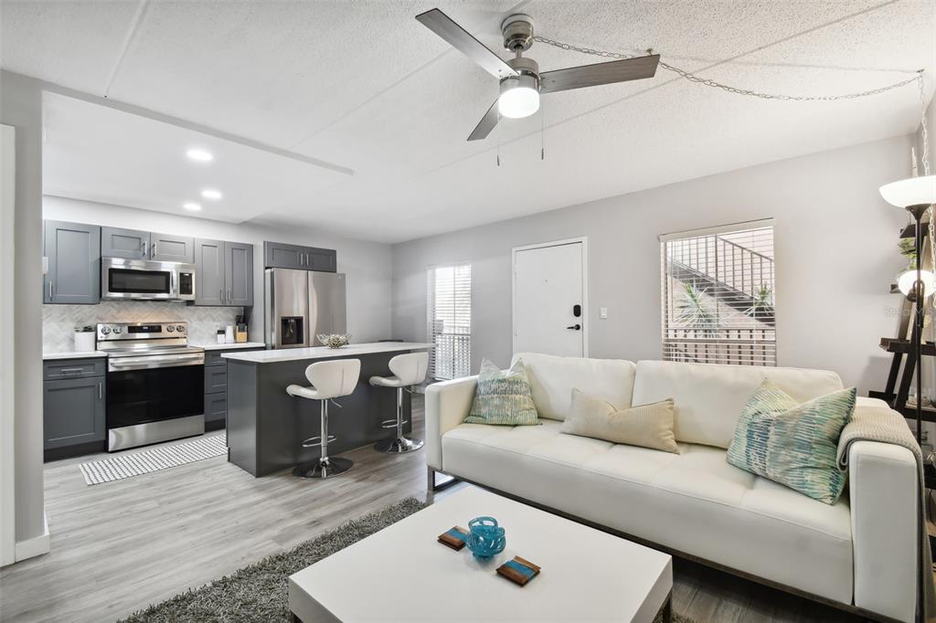8901 Blind Pass Road, Unit 228 St. Pete Beach, FL 33706 - Photo 7 of 29 a living room with stainless steel appliances kitchen island granite countertop furniture and a wooden floor