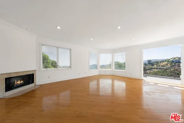 a view of a big room with wooden floor and windows