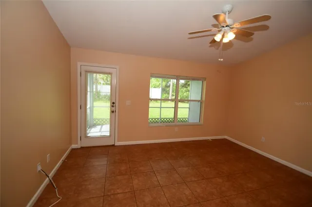 an empty room with chandelier fan and windows