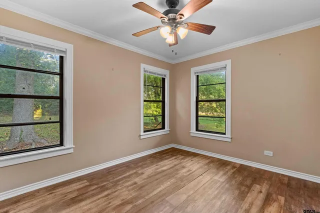 a view of an empty room with window and chandelier fan