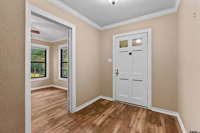 an empty room with wooden floor front door and windows