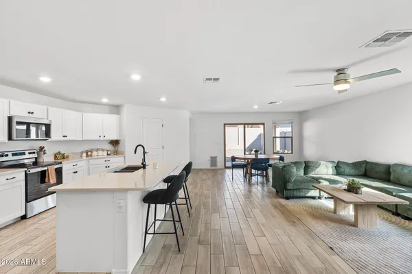 a living room with stainless steel appliances furniture and a wooden floor