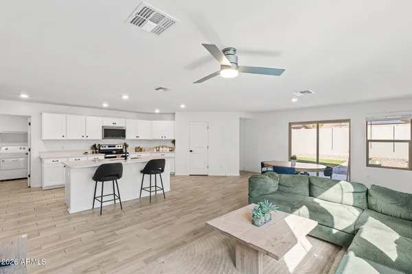 a living room with stainless steel appliances kitchen island granite countertop furniture and a wooden floor