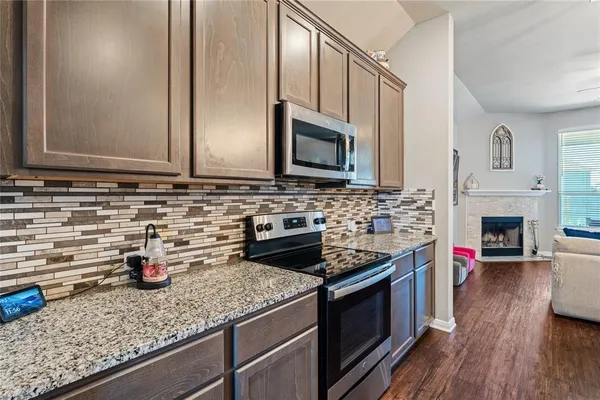 a kitchen with stainless steel appliances granite countertop a stove a sink and a microwave