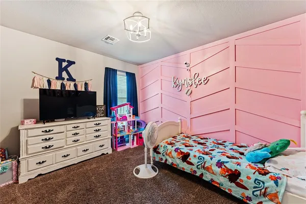 a bedroom with bed and a flat tv screen on dresser