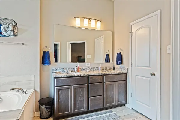 a bathroom with a granite countertop sink a large mirror a and a bathtub