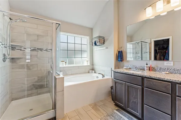 a bathroom with a tub sink mirror and shower