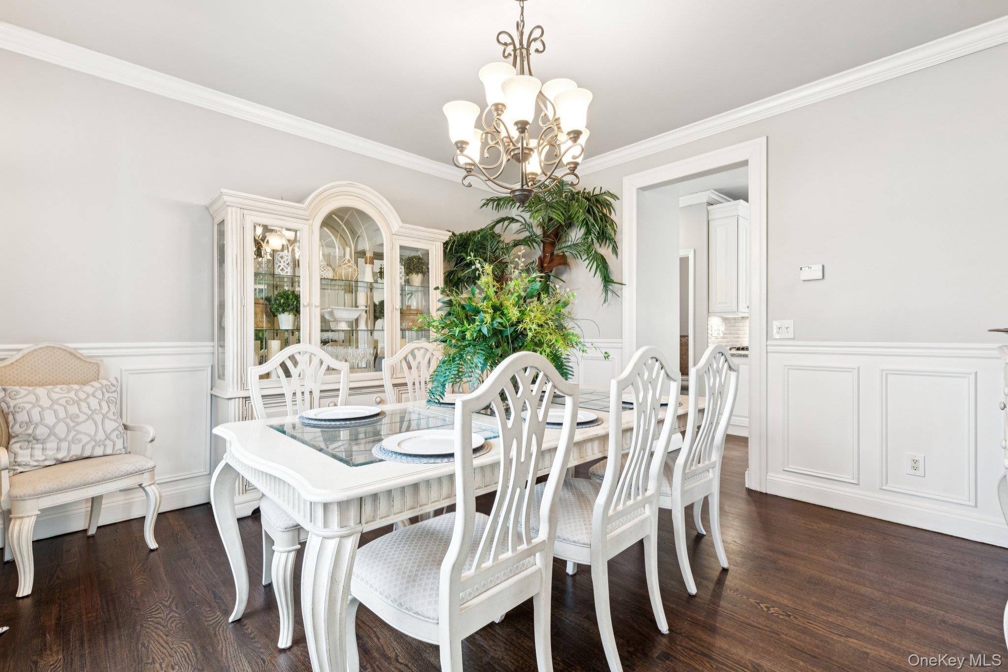 7 Brittany Court Ridge, NY 11961 - Photo 15 of 45 Dining area featuring a wainscoted wall, a decorative wall, a chandelier, crown molding, and dark wood-style flooring