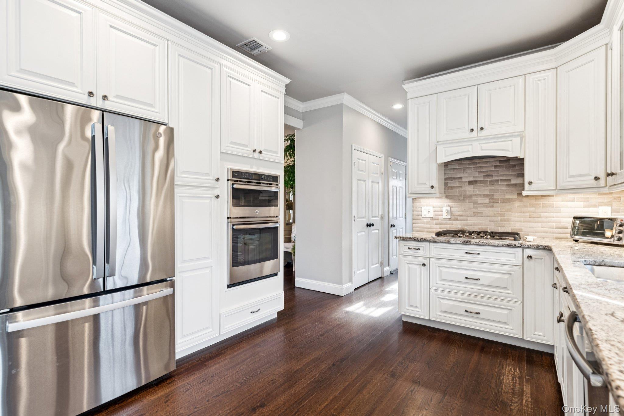 7 Brittany Court Ridge, NY 11961 - Photo 22 of 45 Kitchen featuring stainless steel appliances, light stone countertops, recessed lighting, white cabinets, and ornamental molding