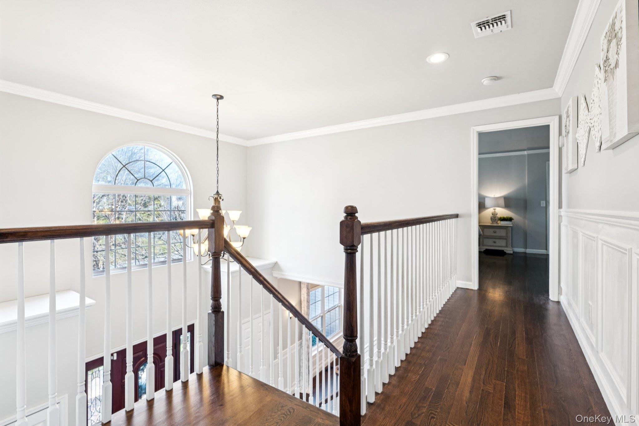 7 Brittany Court Ridge, NY 11961 - Photo 28 of 45 Hall with ornamental molding, dark wood-style flooring, a chandelier, and an upstairs landing