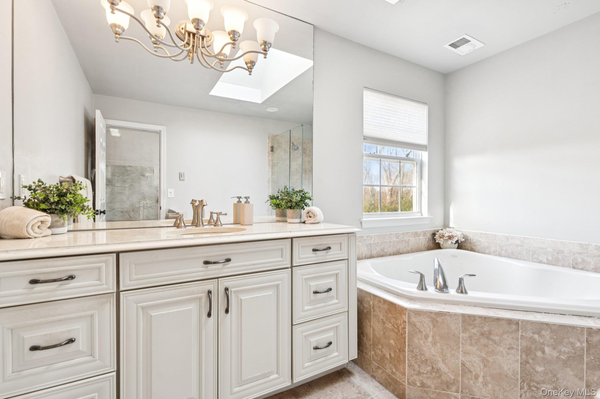 7 Brittany Court Ridge, NY 11961 - Photo 31 of 45 Bathroom featuring vanity, a bath, a skylight, a stall shower, and a chandelier