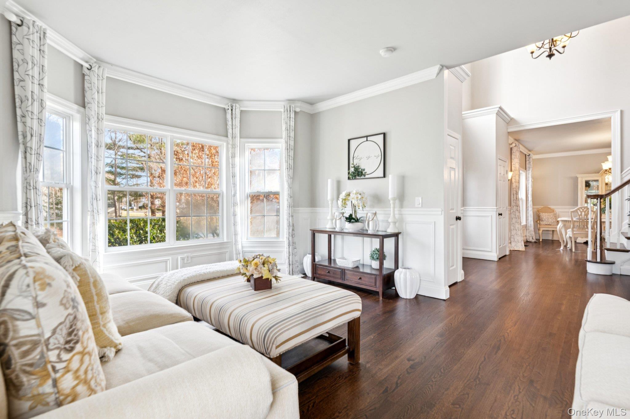 7 Brittany Court Ridge, NY 11961 - Photo 10 of 45 Living room with a wainscoted wall, a decorative wall, ornamental molding, dark wood-type flooring, and stairs