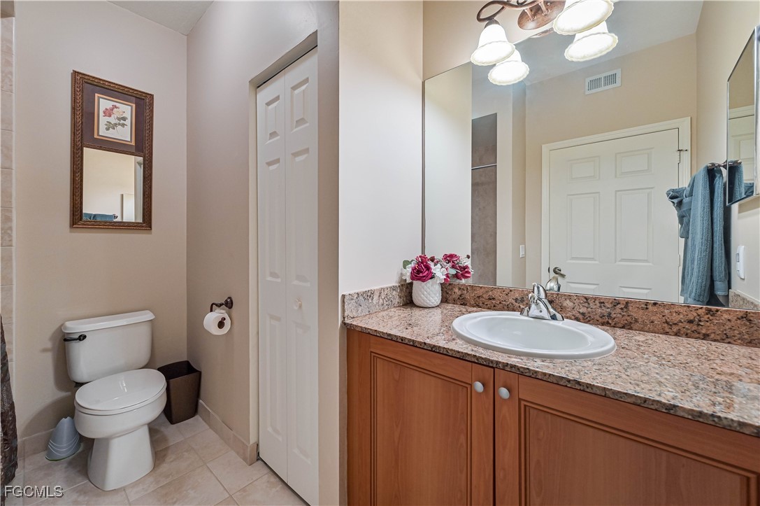 20201 Estero Gardens Circle, Unit 103 Estero, FL 33928 - Photo 19 of 33 a bathroom with a granite countertop sink a toilet and a mirror