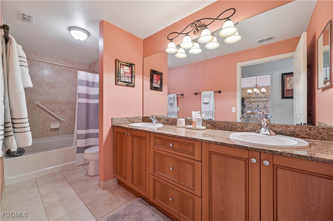 20201 Estero Gardens Circle, Unit 103 Estero, FL 33928 - Photo 24 of 33 a bathroom with a granite countertop sink a toilet a mirror and shower