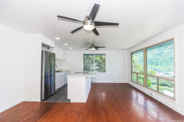 a view of empty room with wooden floor and fan