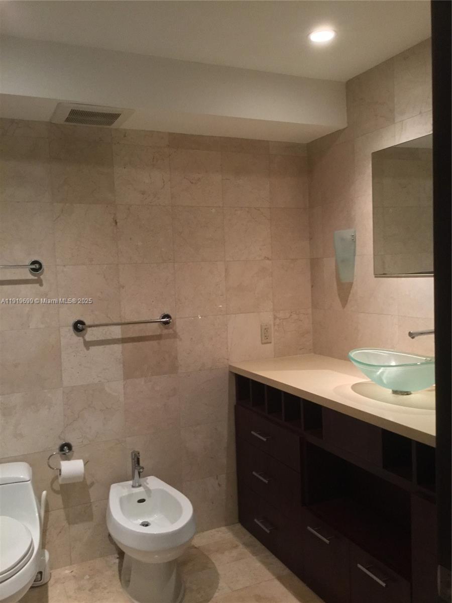 1408 Brickell Bay Drive, Unit 612 Miami, FL 33131 - Photo 18 of 27 a bathroom with a granite countertop sink and a mirror
