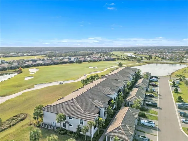 a view of a white house with a small yard plants and a lawn chairs