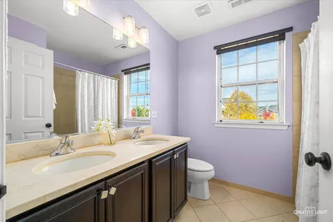 a bathroom with a double vanity sink toilet and a mirror