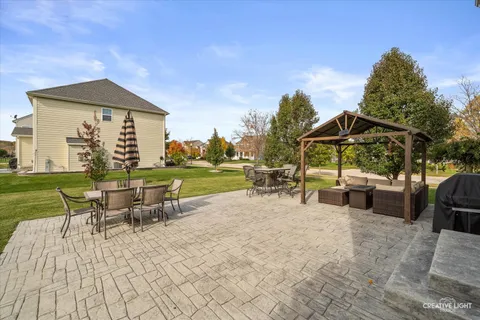 a view of a patio with table and chairs under an umbrella with large trees
