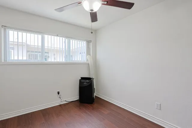an empty room with wooden floor cabinet and windows