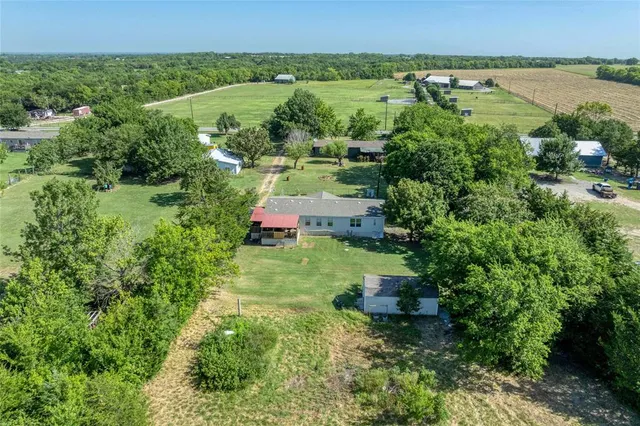an aerial view of residential houses with outdoor space and trees