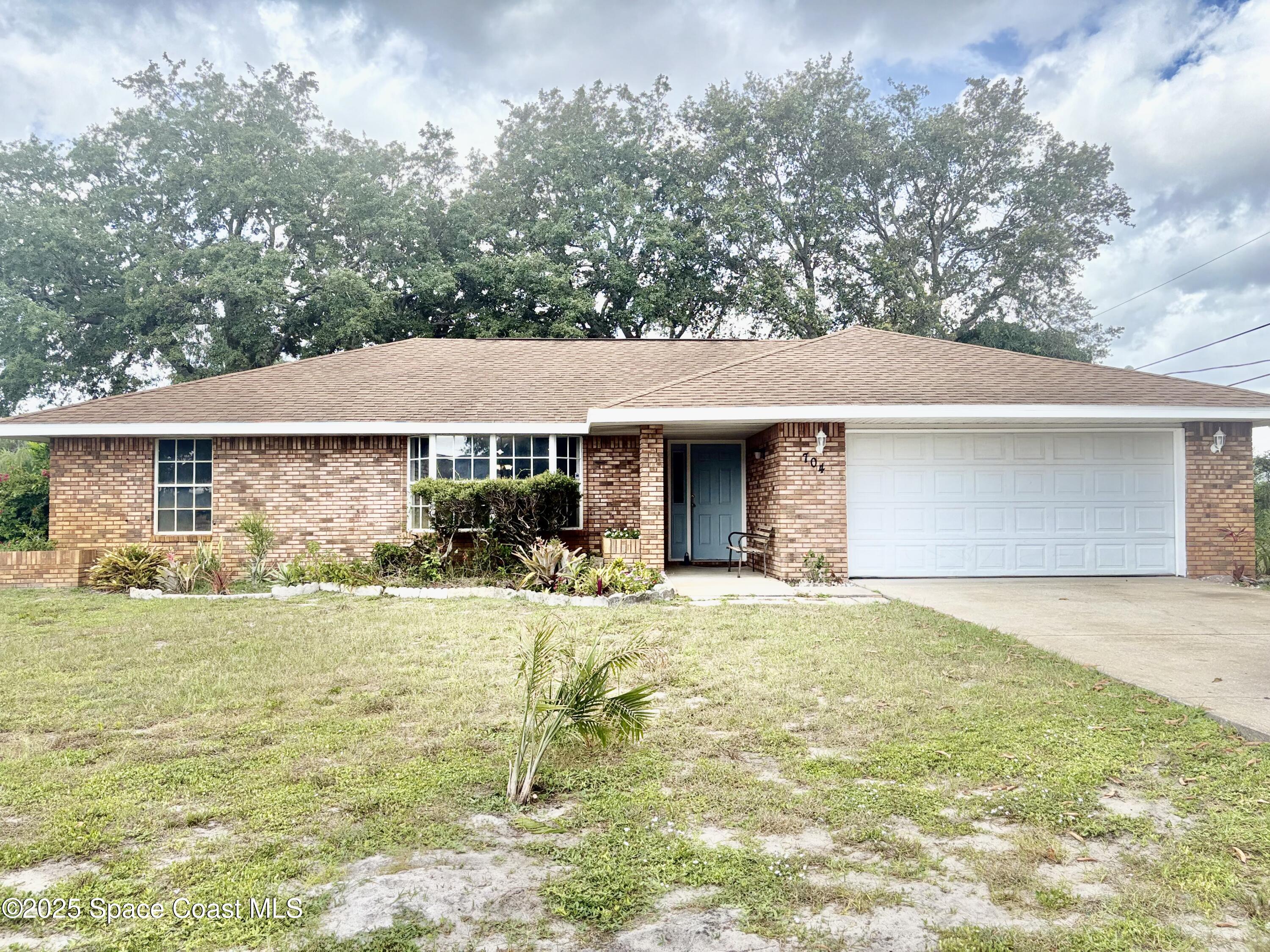 704 Cavio Avenue Northeast Palm Bay, FL 32905 - Photo 1 of 17 a front view of a house with a yard and garage