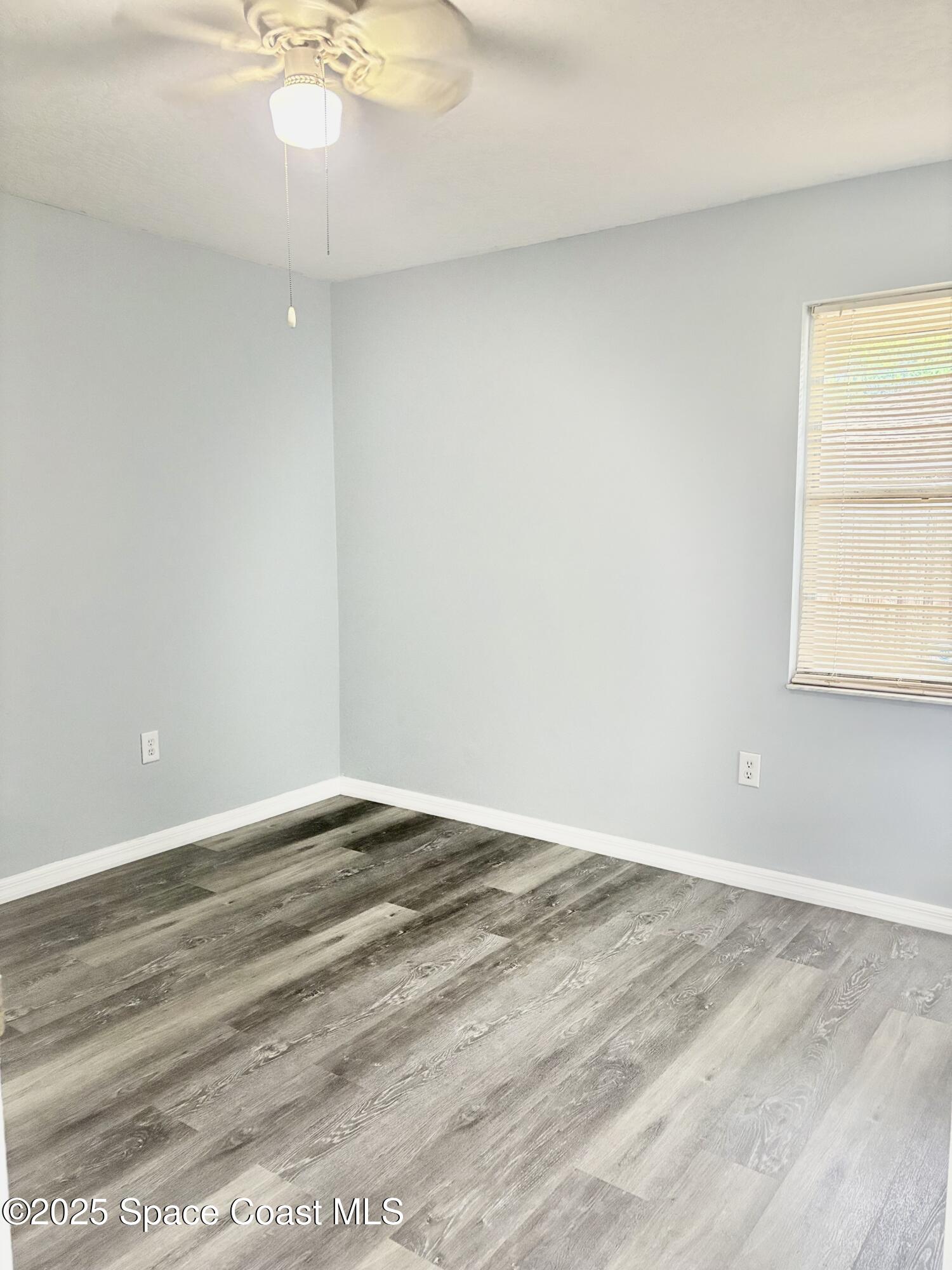 704 Cavio Avenue Northeast Palm Bay, FL 32905 - Photo 11 of 17 an empty room with wooden floor and windows