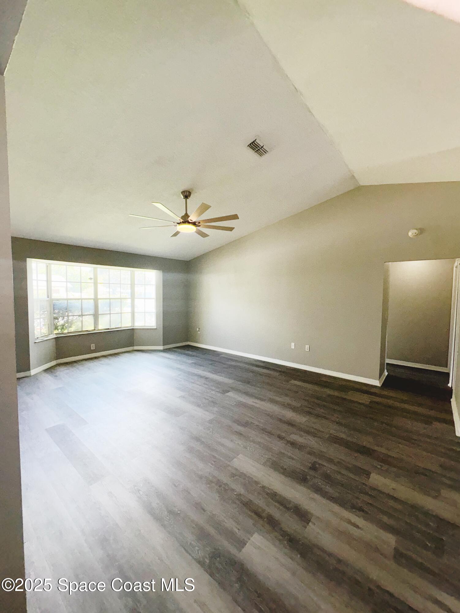 704 Cavio Avenue Northeast Palm Bay, FL 32905 - Photo 4 of 17 an empty room with wooden floor and windows