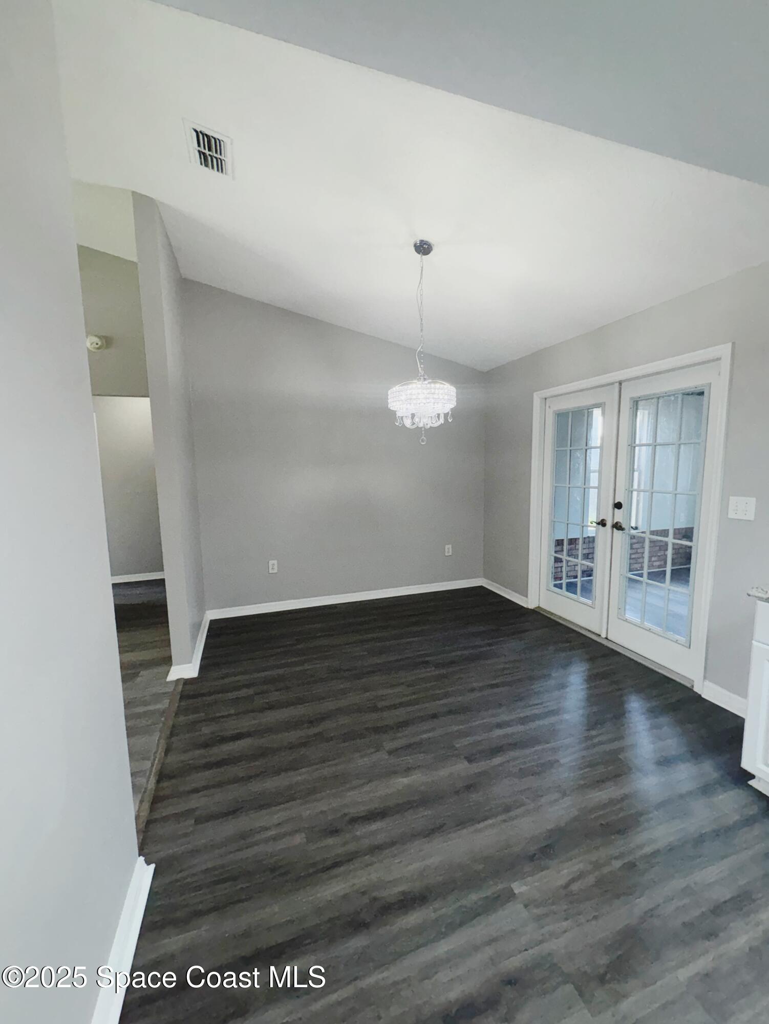 704 Cavio Avenue Northeast Palm Bay, FL 32905 - Photo 7 of 17 an empty room with wooden floor and windows